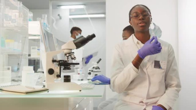 非洲女科学家对她的工作感到满意。看着相机，摘下面具。未来主义的现代实验室