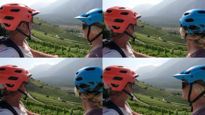骑自行车的夫妇欣赏葡萄园和山脉的景色