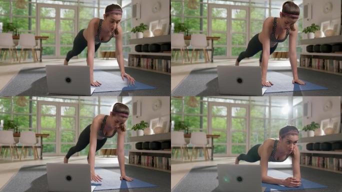 女运动员用笔记本电脑在瑜伽垫上做木板。家庭锻炼