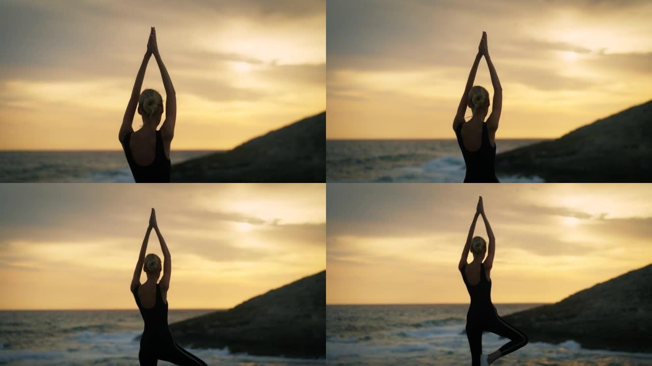 祈祷姿势的女人在海滩做瑜伽。美丽的日落