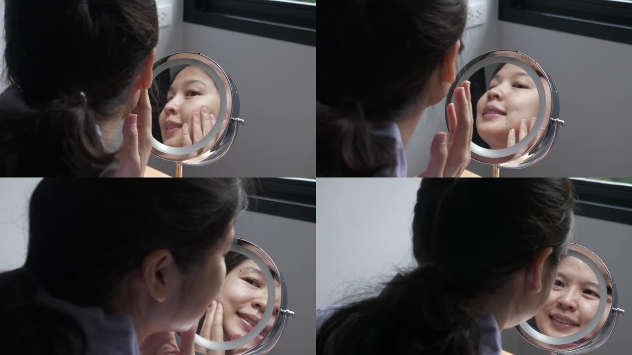 亚洲女性检查面部皮肤状况的反映
