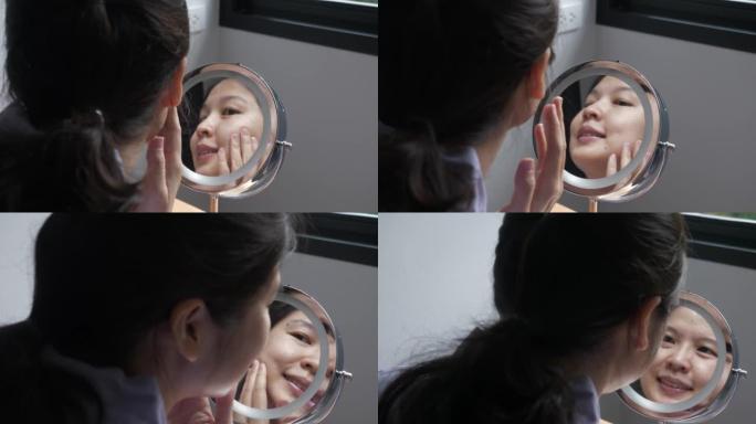 亚洲女性检查面部皮肤状况的反映