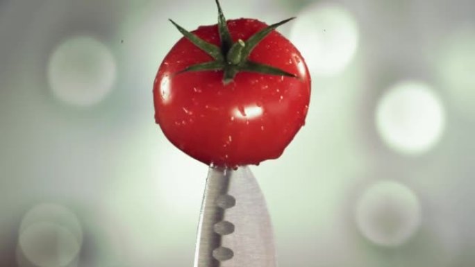 新鲜番茄落在刀子上。白色波克厨房。慢动作。