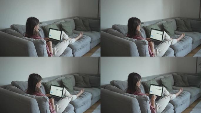 年轻女子在客厅沙发上使用笔记本电脑