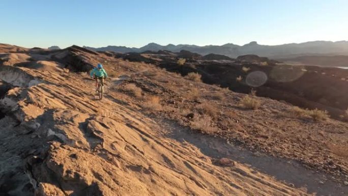 女性山地自行车手沿着沙漠小路