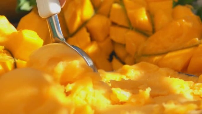 勺子在芒果的背景上慢慢舀冷冻芒果冰淇淋