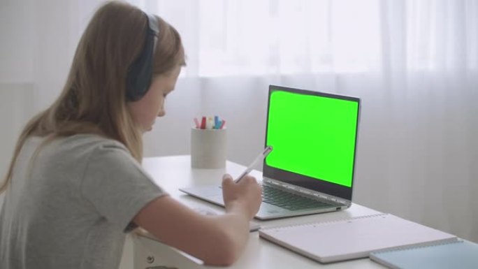 通过互联网为学生提供电子学习，女孩正在通过视频聊天吸引抄写本听力老师，笔记本电脑上的绿屏
