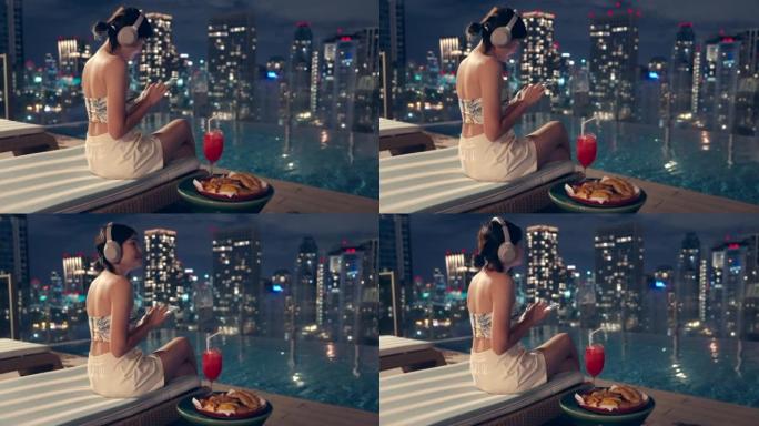 她在泰国曼谷城景高楼的游泳池区听音乐。