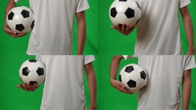 绿屏模型上有足球的无法识别的中东年轻人。自信的运动员站在带足球的chromakey背景模板上。