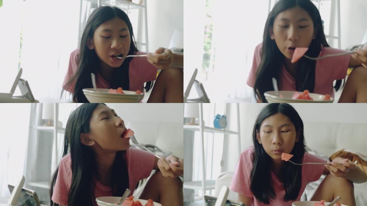 亚洲女孩在家吃窗户附近的西瓜块，健康的饮食生活方式理念。
