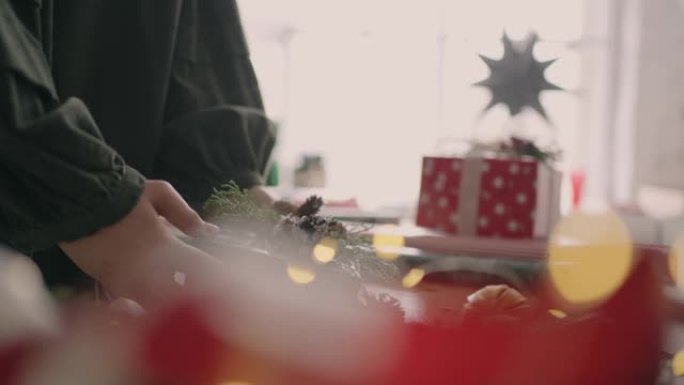 用绳子装饰包裹的盒子。女性在木桌上包装纸板礼品盒，为圣诞节庆祝准备各种装饰物品。细节女性双手系绳