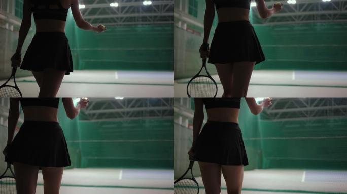 年轻的女网球运动员在室内球场上行走，穿着短裙，投掷球