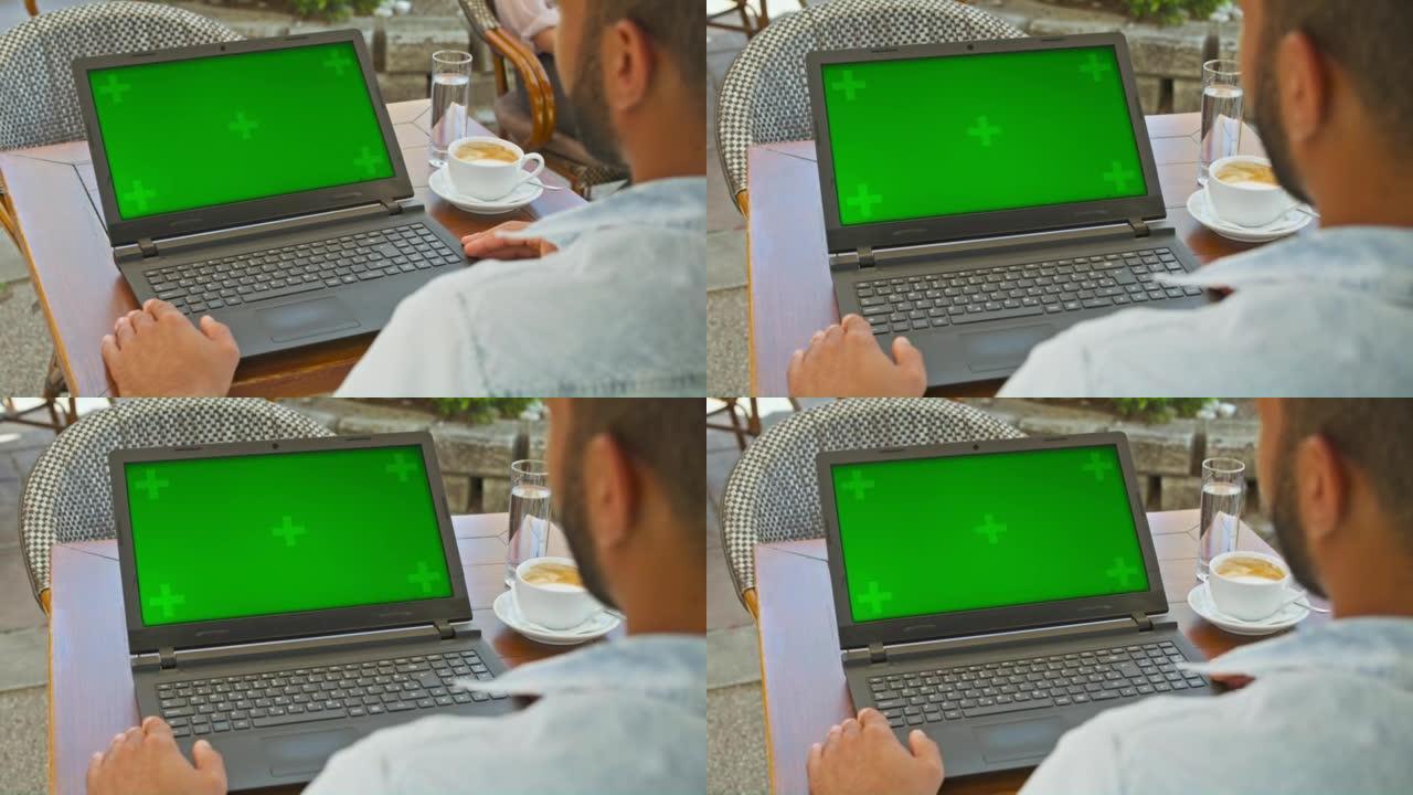 男人坐在咖啡馆里看着笔记本电脑的屏幕