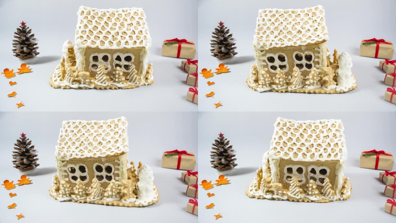 自制姜饼屋，白色甜糖衣绕其轴旋转。装饰有圆锥形、干橘皮和礼品盒。灰色背景。
