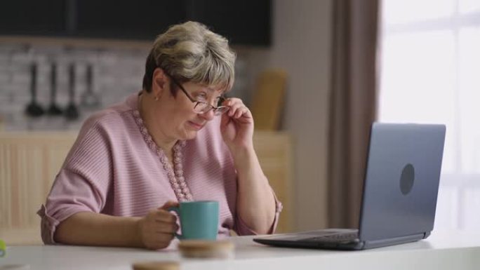 社交网络的老年女性用户的肖像，女人正在通过笔记本电脑打字和发送消息