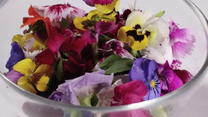 美丽的彩色黄紫罗兰wite红色食用花洒滴在贪婪的花园沙拉番茄大理石桌面碗木勺白色背景