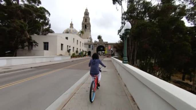 一名妇女骑着自行车穿过城镇的镜头