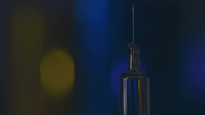 滴落在玻璃疫苗的现代注射器针头上的药滴