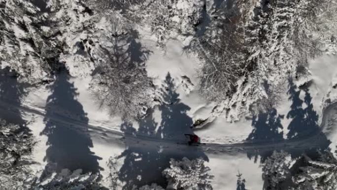 一名男子穿越雪山树木的空中无人机拍摄