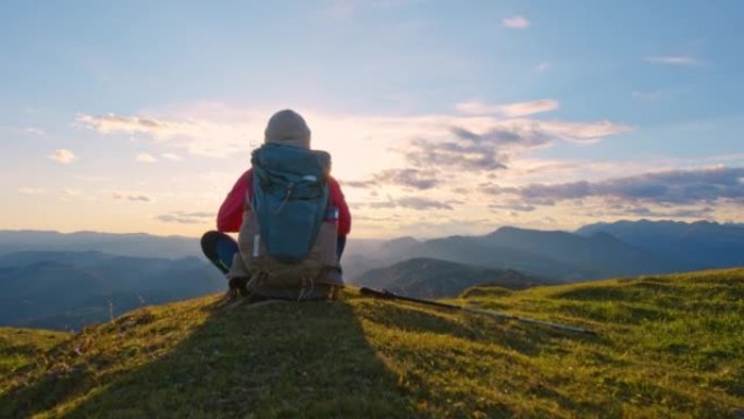 DS女徒步旅行者坐在山顶欣赏夕阳