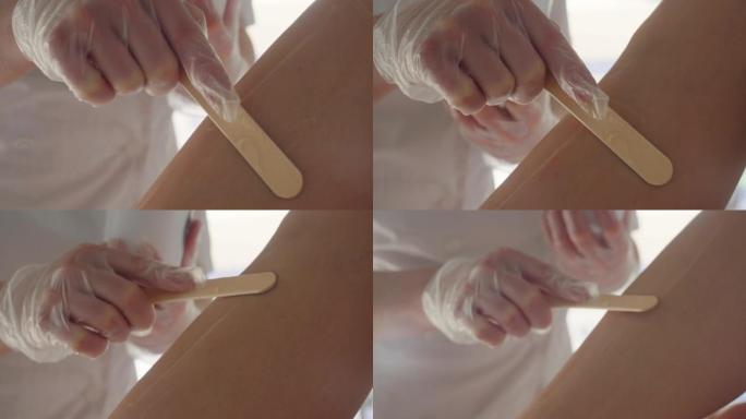 美容师正在使用刮刀在激光脱毛之前在皮肤上涂抹凝胶，现代技术