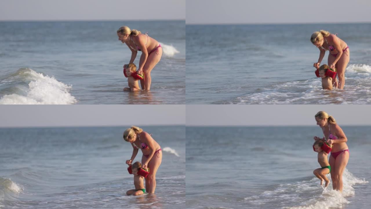 在一个夏天的晚上，妈妈和婴儿在袖子里玩耍，把他扔向海浪