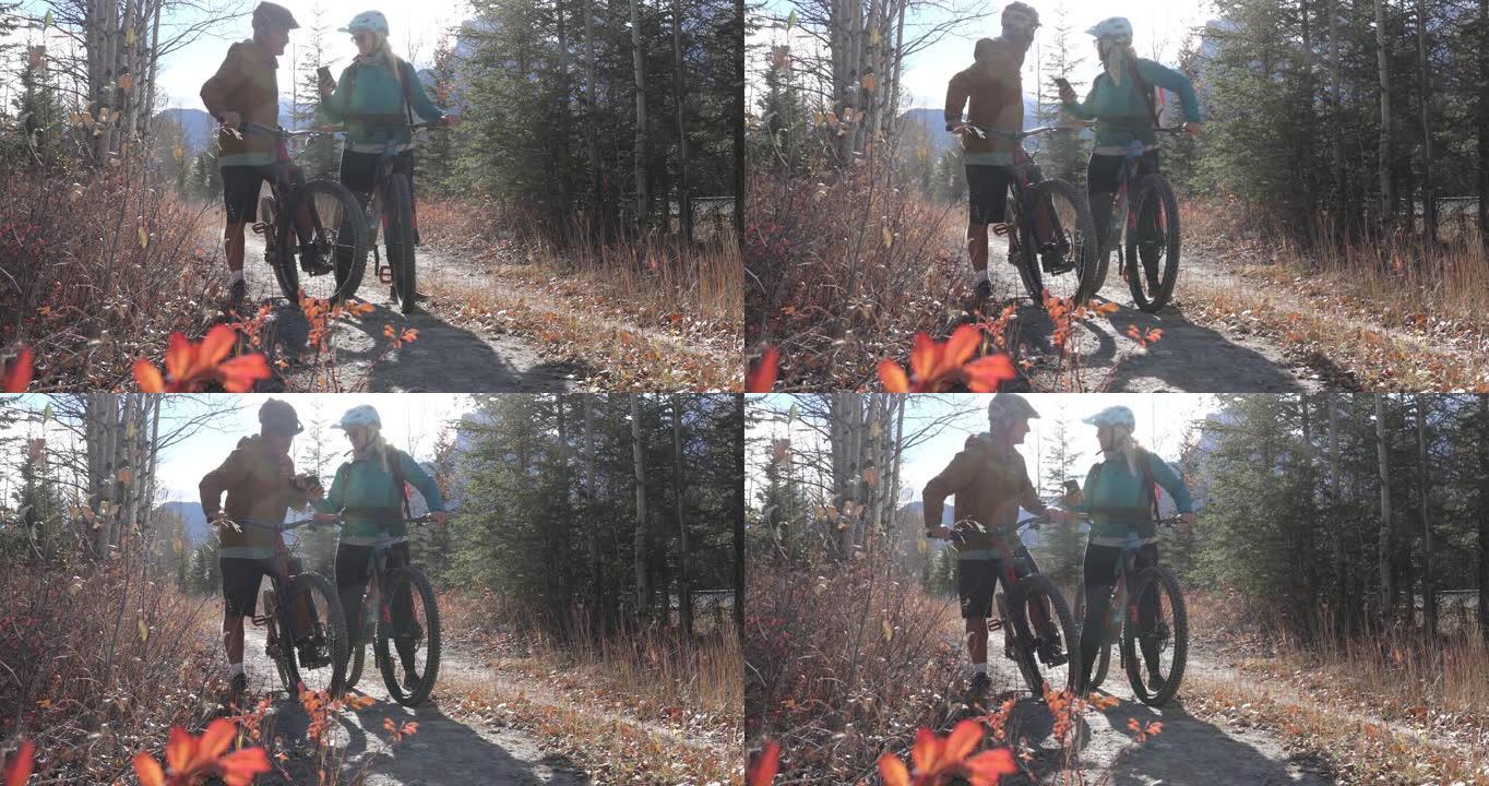 山地自行车夫妇在高山小径上停下来检查方向，远处的山脉