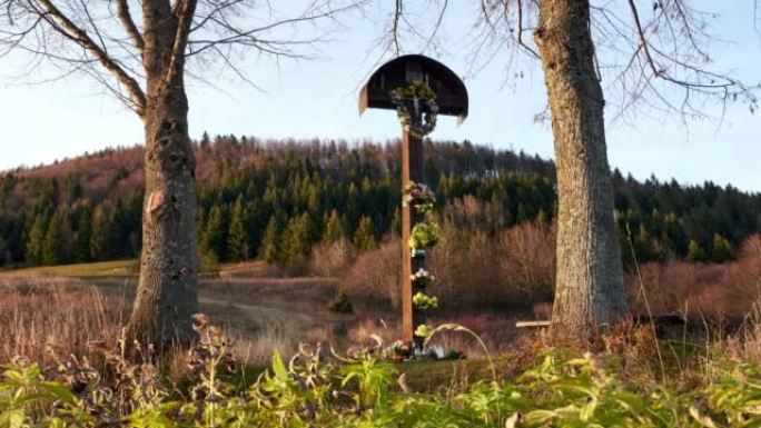 一个古老的木制基督教十字架，上面挂着花圈和鲜花。树丛中的精神地方。4k延时