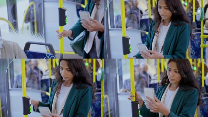 男人坐在公共汽车上的窗户旁边，一个女人站着看着她的手机