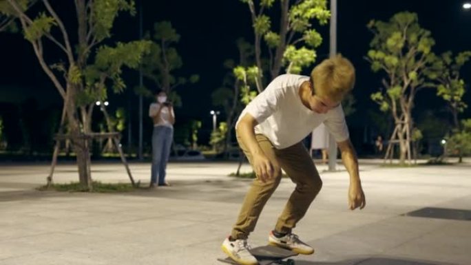 播放过程中拍摄幕后视频。亚洲青年男子在夜城溜冰场滑板