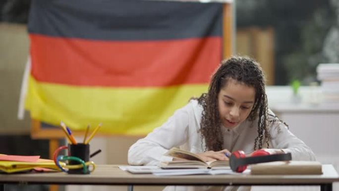 吸收非裔美国女孩在学校读书的肖像，背景是德国国旗。聪明执着的女学生在欧洲的教室里学习。教育和生活方式