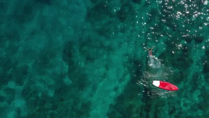 空中无人机拍摄了一名在绿松石水中游泳的妇女