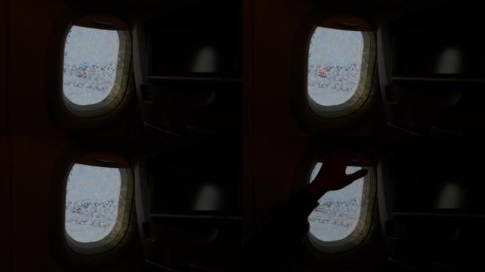 飞机在起飞前除冰时，机舱内的舷窗为4k镜头。女人的手关闭阴影以使整个黑暗。