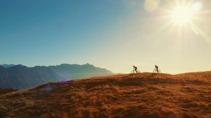 山地自行车手在惊人的日落灯光下越野骑行