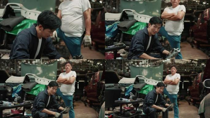 高级机械师和他的儿子在汽车服务中对着相机摆姿势的肖像