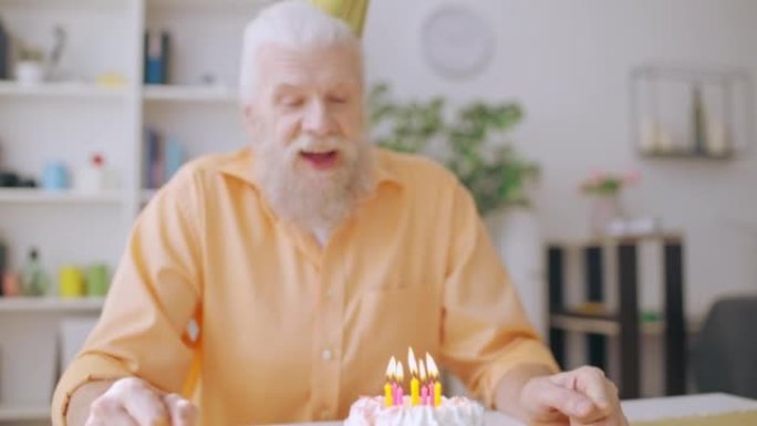 老人在生日蛋糕上吹蜡烛，许愿，孤独的爷爷