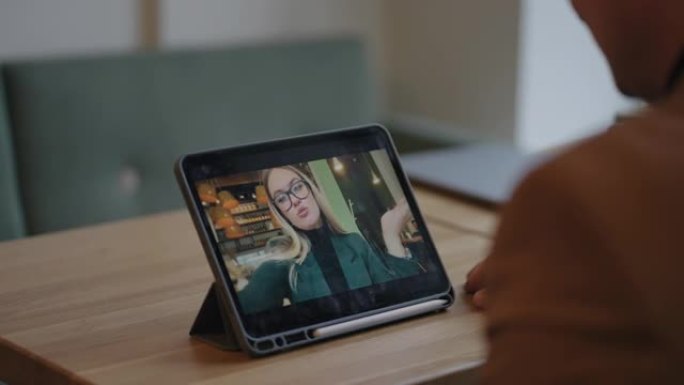 快乐的女人在平板电脑上通过视频会议打电话给男友，男人在咖啡馆里使用小工具