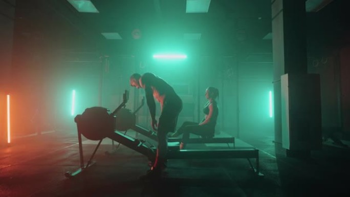健身房，男人和女人正在黑暗的大厅里用训练器械训练，运动健康