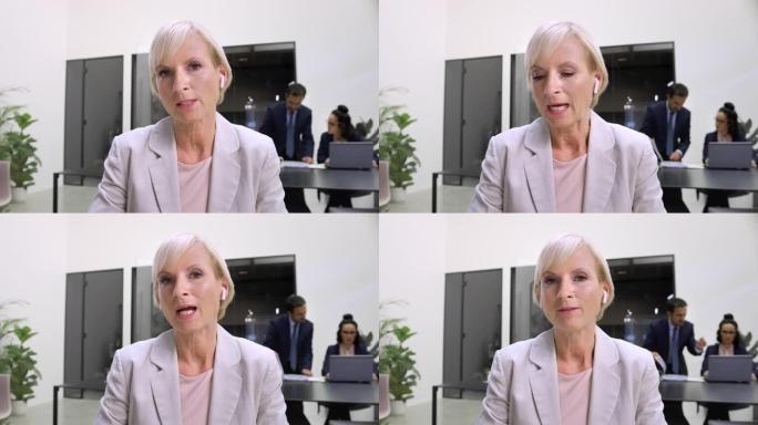 LD成熟的白人妇女坐在办公室里，在视频会议上讲话