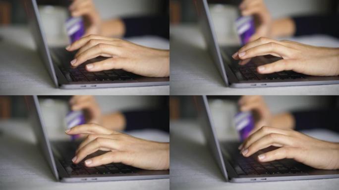 女人的手在笔记本电脑上输入信用卡进行在线购物的详细照片