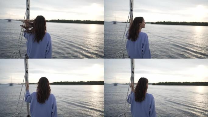 日落时，年轻女子从帆船望向海湾对面