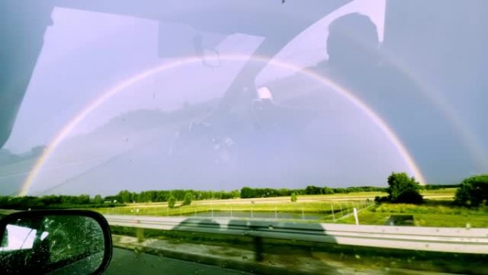 POV汽车驾驶。在雨中追逐彩虹