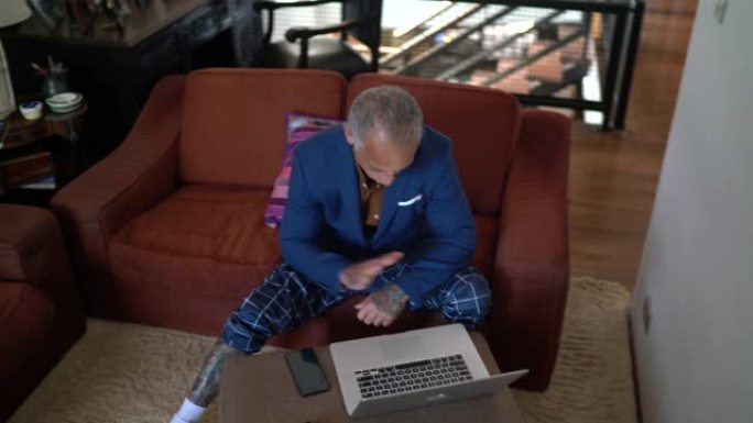 商人在家工作，在参加视频通话时使用pajamas的裤子