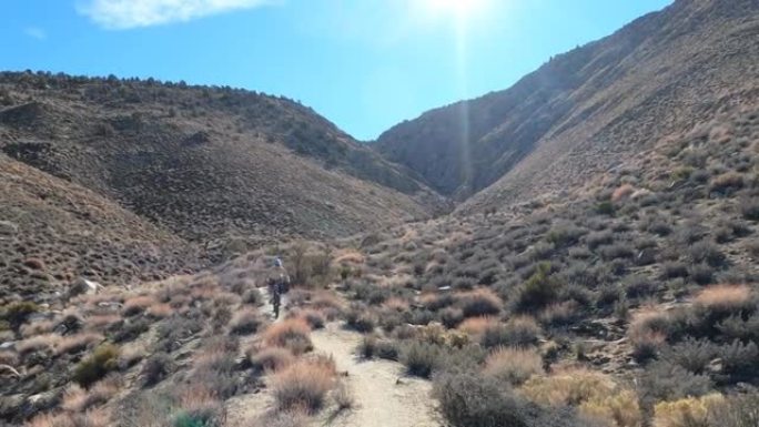 一名男子山地自行车手沿着狭窄的沙漠轨道行驶