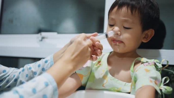 妈妈帮她的小男孩用盐水做鼻腔冲洗清洁