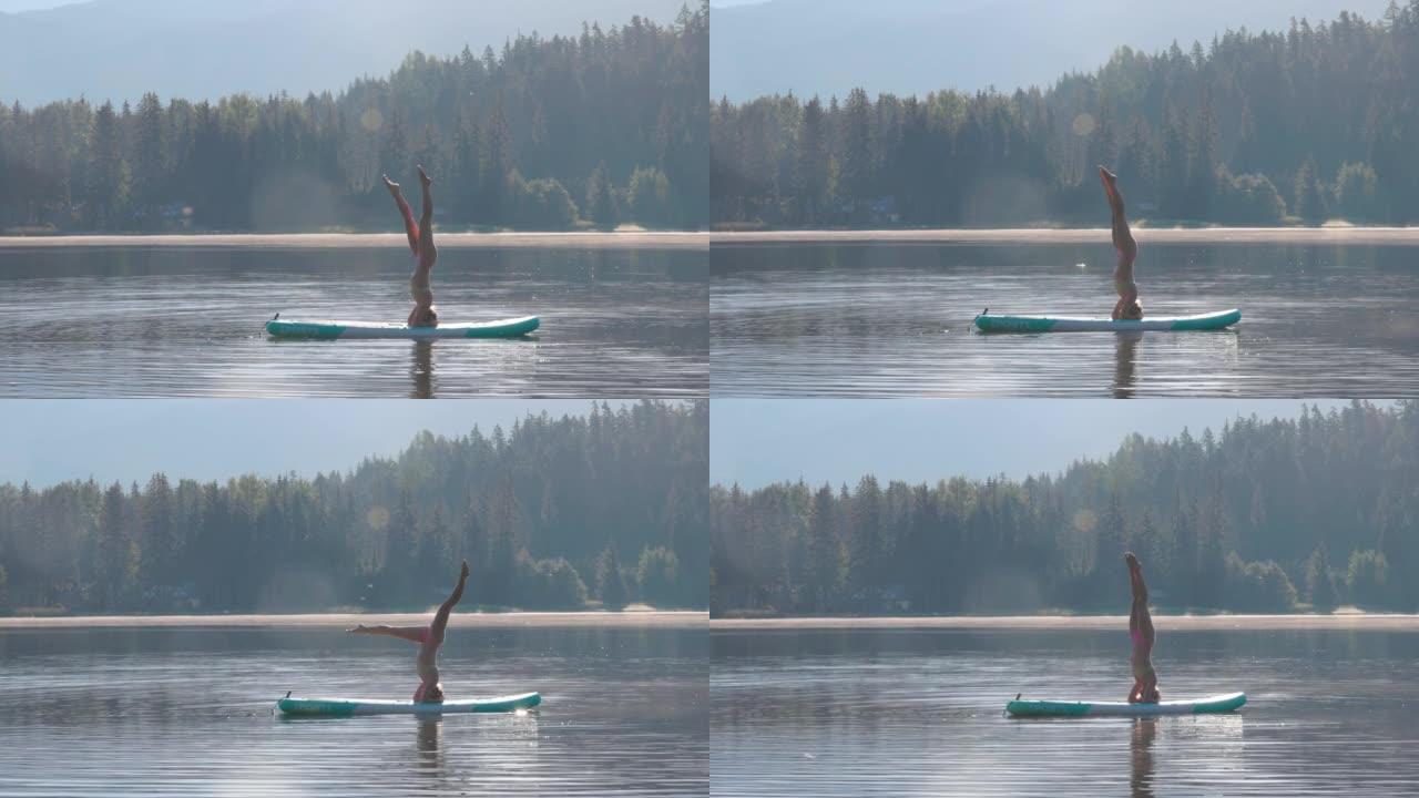 年轻女子在站立桨板 (SUP) 上执行瑜伽动作