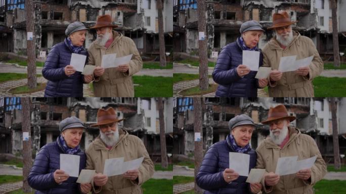 年长的悲伤的男人和女人站在照片的背景下，烧毁的住宅大楼外面。老夫妇在被炸毁的乌克兰城市回忆往事的画像