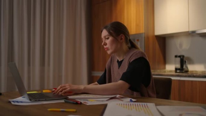 侧视图一名女性在家庭办公室里用笔记本电脑远程工作，并在图表上记录数据，一名商业经济学家分析师。写下做