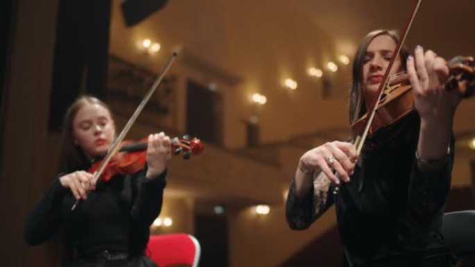 两名女小提琴手在老歌剧院，剧院管弦乐队的现场演奏音乐