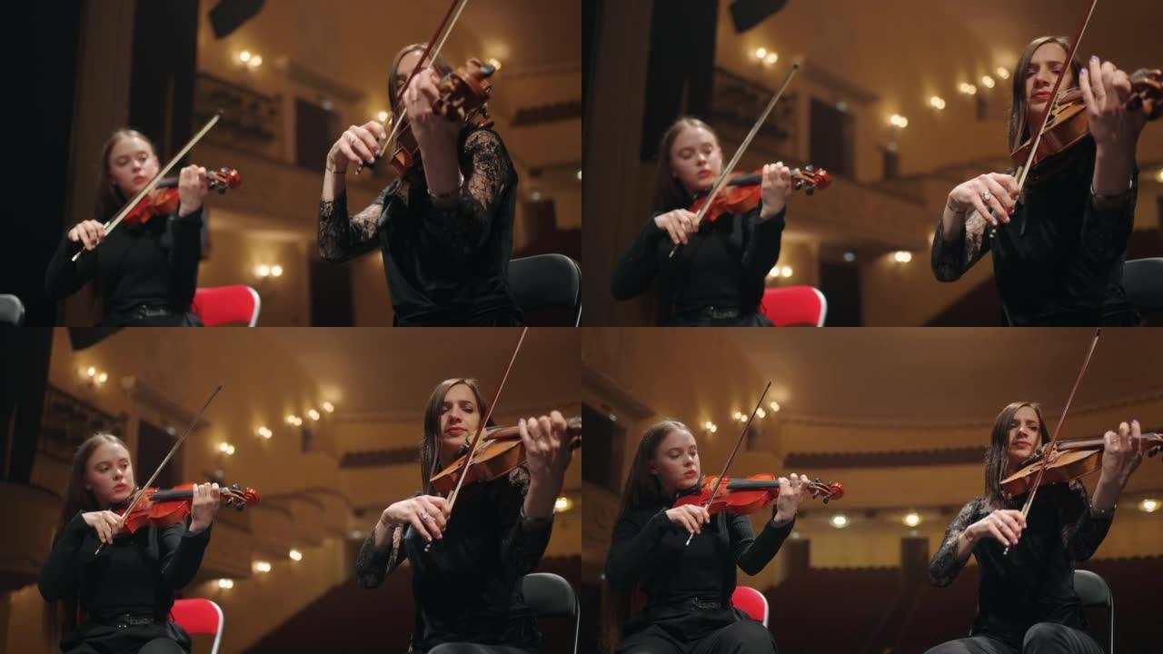 两名女小提琴手在老歌剧院，剧院管弦乐队的现场演奏音乐
